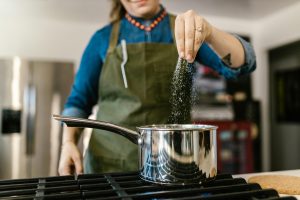 Woman adding salt to pot on stove